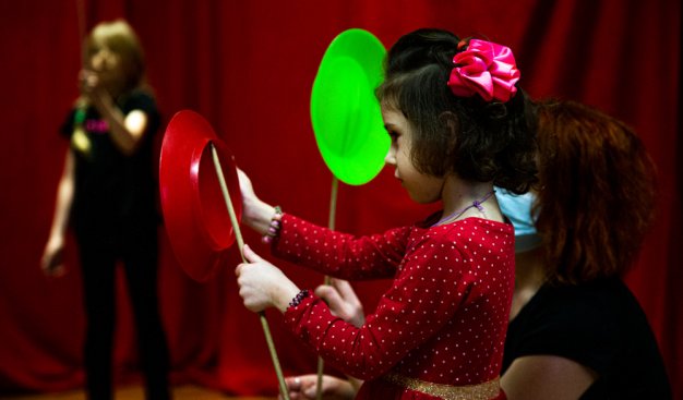 Dziewczynka w czerwonej sukience, ucząca sięsztuczki cyrkowej - kręcenia tależem