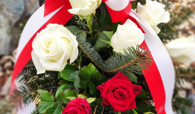 Zdjęcie wieńca wykonanego z białych i czerwonych róż z biało-czerwoną szarfą
