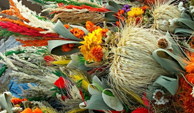 Wielkanocne palmy wykonane z naturalnych materiałów, sztywnych traw, zbóż, kolorowych kwiatów.