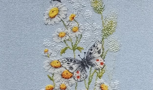 Wyszywany  obraz - kwiaty polne i siedzące na nich dwa motyle.