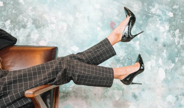 widok na nogi kobiety w czarnych szpilkach i eleganckich, szarych spodniach w kratkę