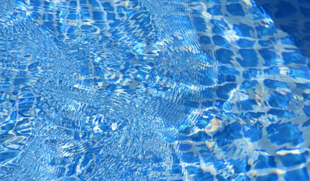 Mieniąca się błękitna tafla wody w basenie.