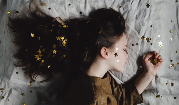 śpiąca dziewczynka z czarnymi długimi włosami, w których pełno jest złotych gwiazdek