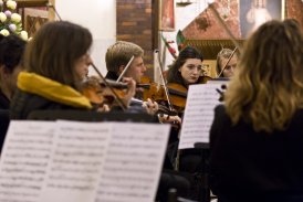 Fotografia przedstawia grupę muzyków, którzy grają na skrzypcach w jednym z kościołów Mistrzejowickich. Na drugim planie widzimy nuty, które znajdują się na stojaku.