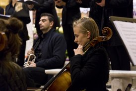 Fotografia przedstawia zespół muzyczny. NA pierwszym planie widzimy kobietę, która gra na dużych skrzypcach.