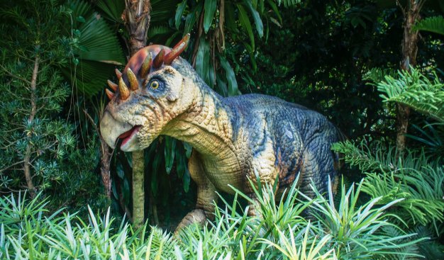 Figura dinozaura pośrodku sztucznej roślinności.