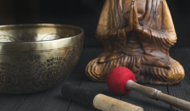 Na zdjęciu widać figurę buddy, buddyjski metalowy półmisek i narzędzia do naczynia.