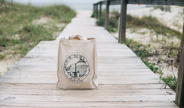 Zdjęcie torby stojącej na na drewnianej ścieżce prowadzącej na plażę.