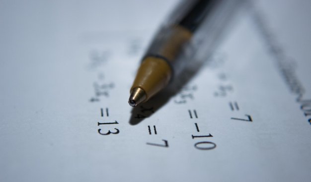 Zdjęcie przedstawiające długopis położony na kartce z równaniami matematycznymi