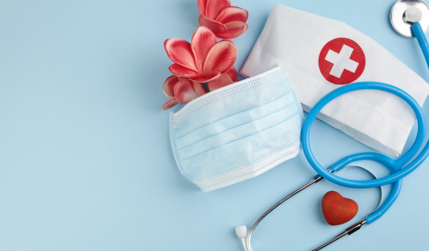 stetoskop, maseczka ochronna, czepek pielęgniarski, kwiaty i czerwone serce