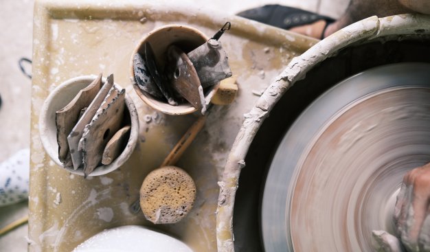 Zdjęcie przedstawia koło ceramiczne i narzędzia służące do wykonania ceramiki.
