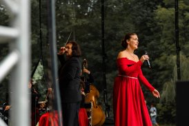 Zdjęcie solistki, w czerwonej sukni na śpiewającej na scenie