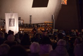 Zdjęcie z koncertu na pierwszym planie widoczni są ludzie siedzący w ławach kościelnych, na dalszym planie widoczni są występujący - Antonina Krzysztoń oraz grający na gitarze Michał Majerczyk, na tle ołtarza.