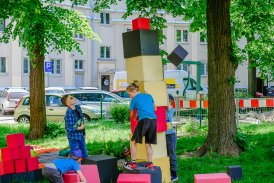 Na zdjęciu widać dwóch chłopców budujących wieżę z kolorowych brył sześciennych.
