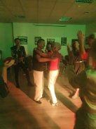 Fotografia przedstawia grupkę ludzi, którzy tańczą na przyjęciu. W centrum znajduję się starsza para, która tańczy.