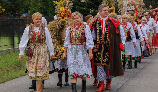 Zdjęcie osób w tradycyjnych strojach krakowskich niosących wieńce dożynkowe