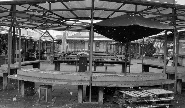 Czarno-białe zdjęcie przedstawiające opustoszały, pokrywający się śniegiem plac targowy na os. Wandy.