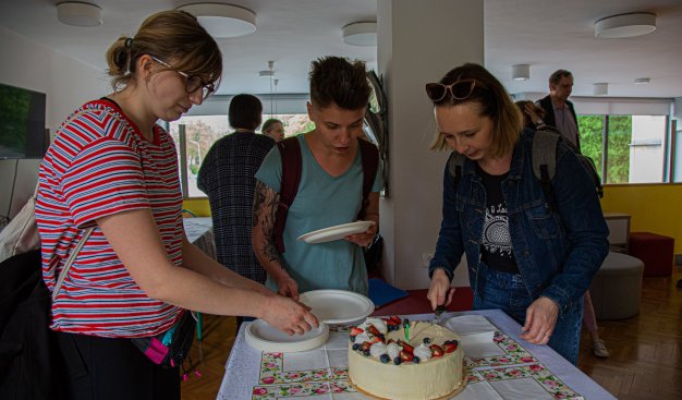 Grupka trzech osób pochylających się nad tortem