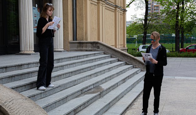 Zdjęcie przedstawiające dwie osoby stojące na schodach przed Teatrem Ludowym - odgrywają scenę z Romeo I Julia