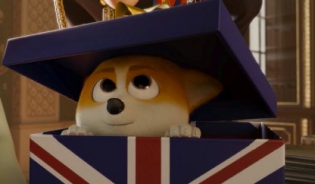 Kadr z filmu Corgi, psiak królowej przedstawiający psa rasy corgi siedzącego w pudełku we flagę brytyjską. Pies wychyla głowę z pudełka